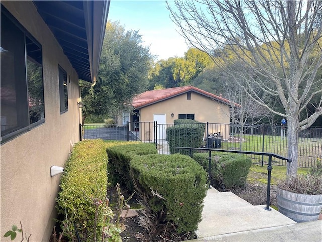 view of side of property featuring a tile roof, fence, and stucco siding