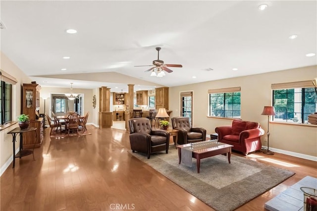 living room featuring light wood-type flooring, plenty of natural light, decorative columns, and vaulted ceiling