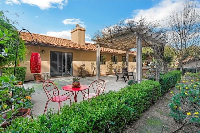 back of house featuring a patio, a pergola, a tiled roof, stucco siding, and a chimney