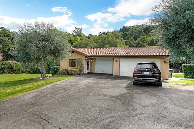 ranch-style house featuring aphalt driveway, a tile roof, stucco siding, a front yard, and a garage