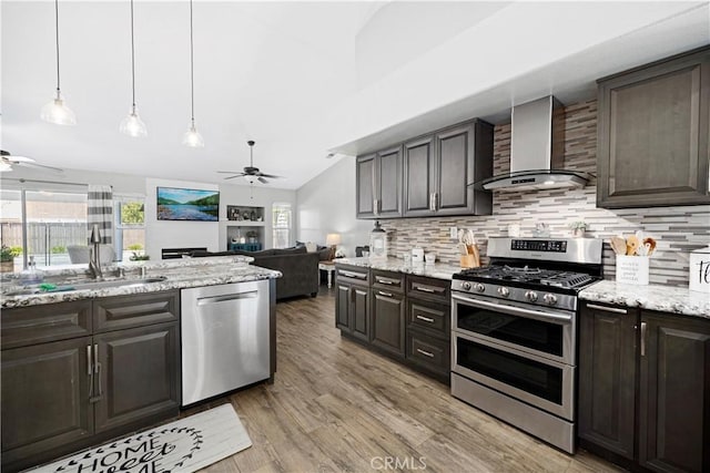 kitchen featuring appliances with stainless steel finishes, a sink, wall chimney range hood, and a ceiling fan