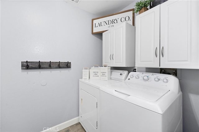 washroom with cabinet space, baseboards, wood finished floors, and washing machine and clothes dryer