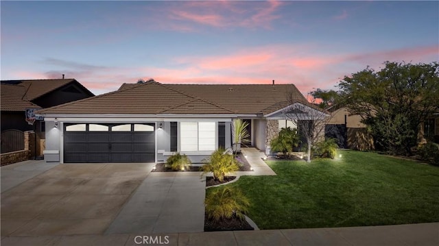 ranch-style home with a garage, driveway, a tiled roof, a front yard, and stucco siding