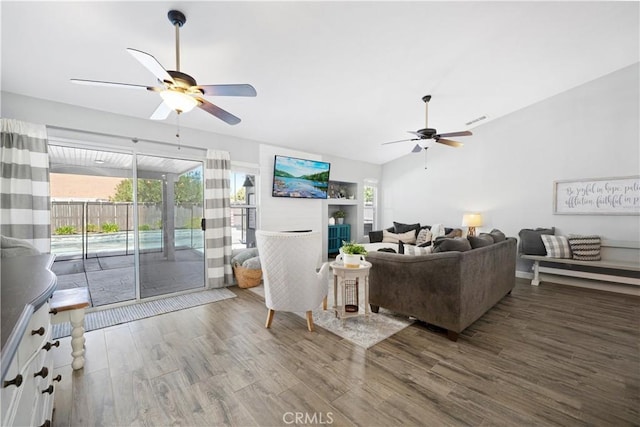 living area featuring visible vents, ceiling fan, wood finished floors, vaulted ceiling, and a fireplace