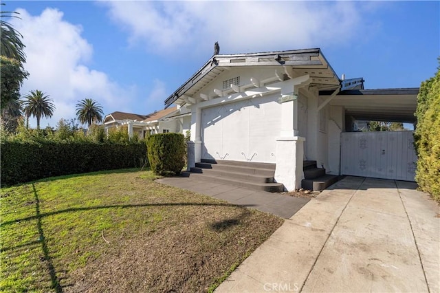 view of side of property with a yard, a carport, concrete driveway, and stucco siding