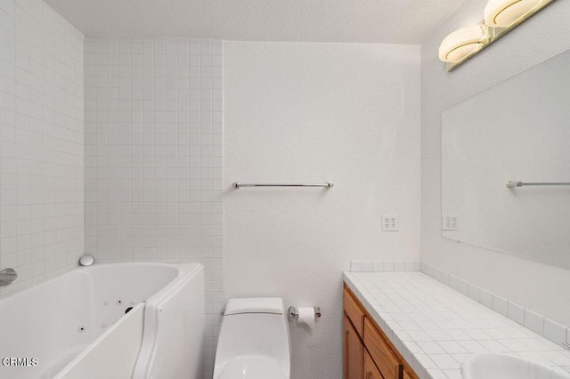 full bathroom featuring toilet, a tub with jets, a textured ceiling, and vanity