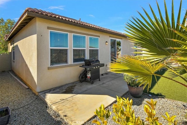 view of side of property featuring a patio area, a tiled roof, and stucco siding