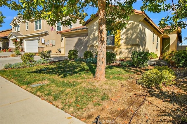 mediterranean / spanish house with concrete driveway, a front yard, a tiled roof, and stucco siding