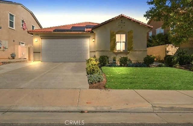 mediterranean / spanish house featuring stucco siding, an attached garage, roof mounted solar panels, driveway, and a tiled roof