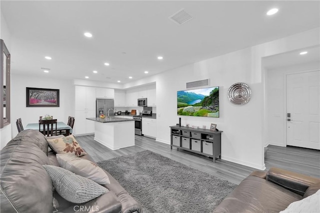 living room with light wood-type flooring, recessed lighting, and visible vents