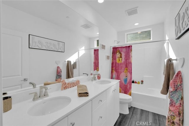 full bathroom featuring toilet, double vanity, visible vents, and a sink