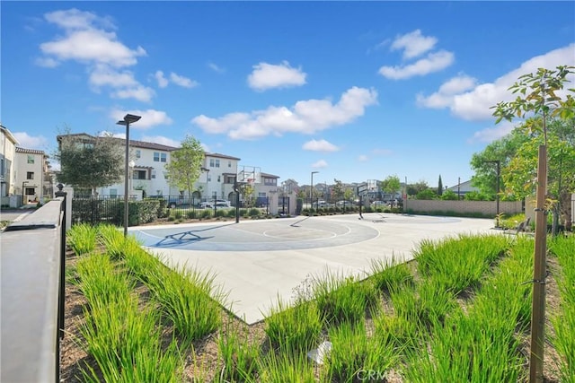 view of basketball court featuring community basketball court, fence, and a residential view