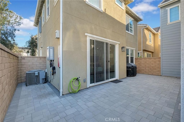 back of house featuring central AC unit, a patio area, fence, and stucco siding