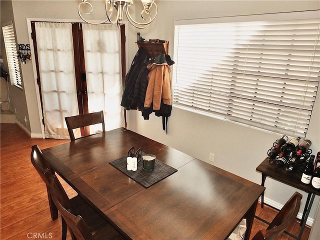 dining area with baseboards, french doors, wood finished floors, and a notable chandelier