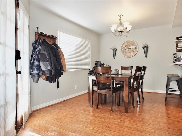 dining room with light wood-type flooring, baseboards, and a notable chandelier