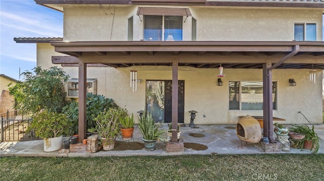 rear view of property featuring stucco siding and a patio