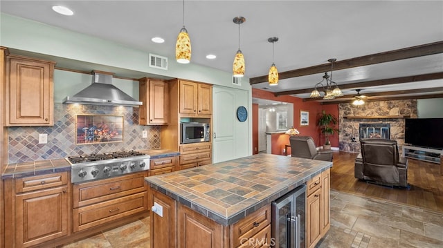 kitchen featuring visible vents, decorative backsplash, wall chimney exhaust hood, wine cooler, and stainless steel appliances