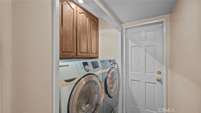 laundry room featuring a textured wall, cabinet space, and washer and dryer