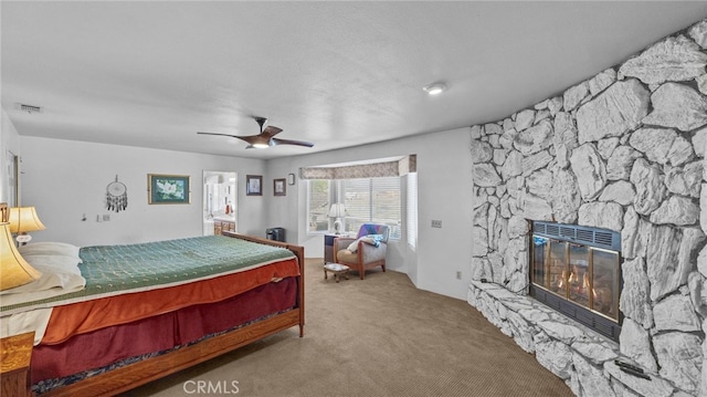 carpeted bedroom featuring a ceiling fan, visible vents, and a fireplace