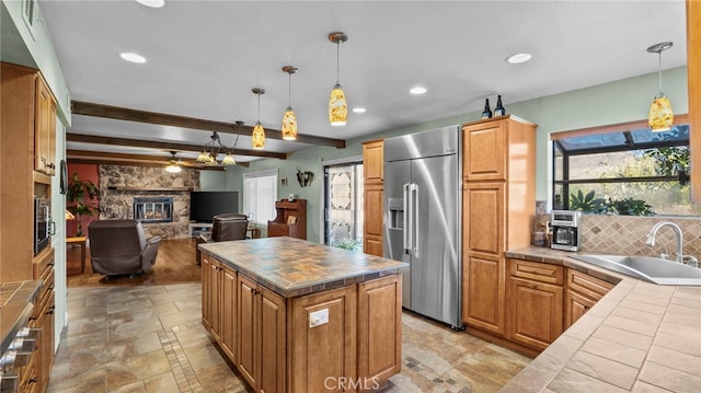 kitchen with appliances with stainless steel finishes, tile counters, open floor plan, and a sink