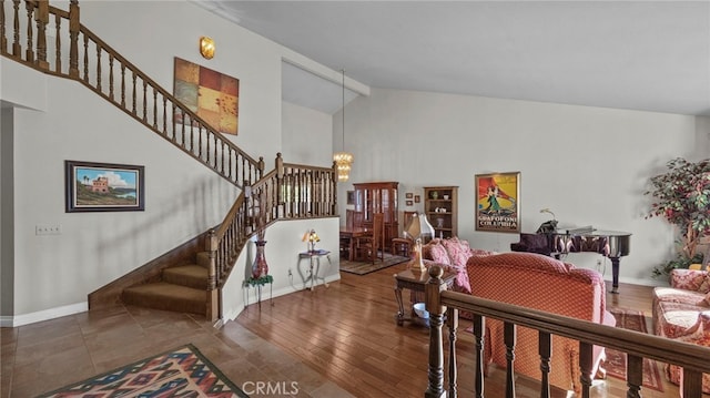 interior space with a notable chandelier, wood finished floors, high vaulted ceiling, baseboards, and stairs