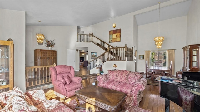 living area featuring stairs, hardwood / wood-style flooring, a high ceiling, and an inviting chandelier