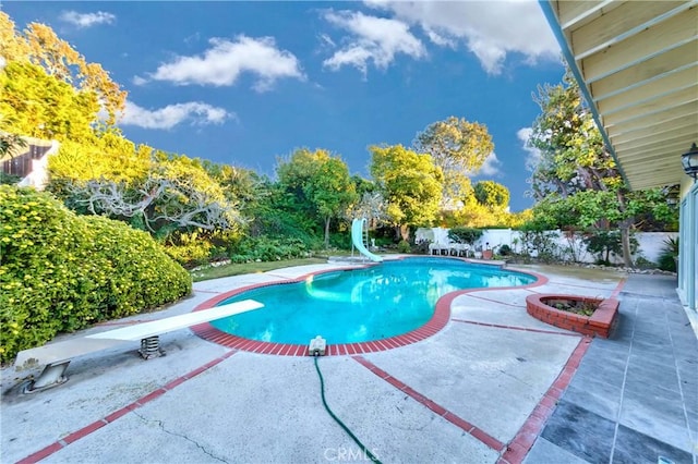 view of pool featuring a fenced in pool, a patio area, fence private yard, a water slide, and a diving board