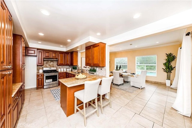 kitchen featuring light stone counters, a breakfast bar, stainless steel range oven, a sink, and a peninsula