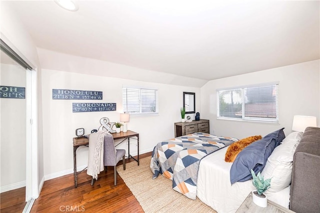 bedroom with lofted ceiling, multiple windows, baseboards, and wood finished floors