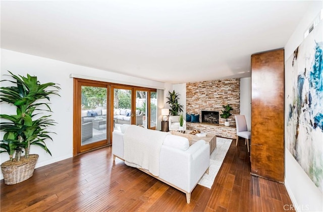 living room featuring baseboards, french doors, dark wood-style flooring, and a stone fireplace