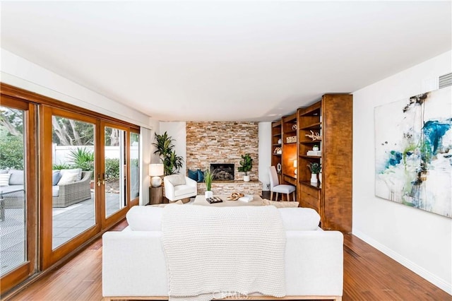 living area with light wood-style flooring, a fireplace, baseboards, and french doors