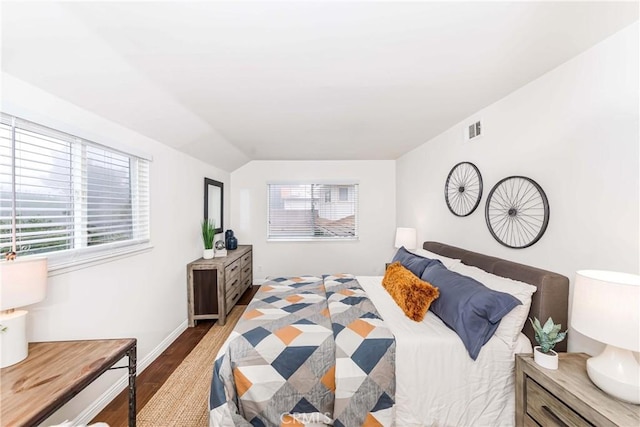 bedroom featuring lofted ceiling, visible vents, baseboards, and wood finished floors