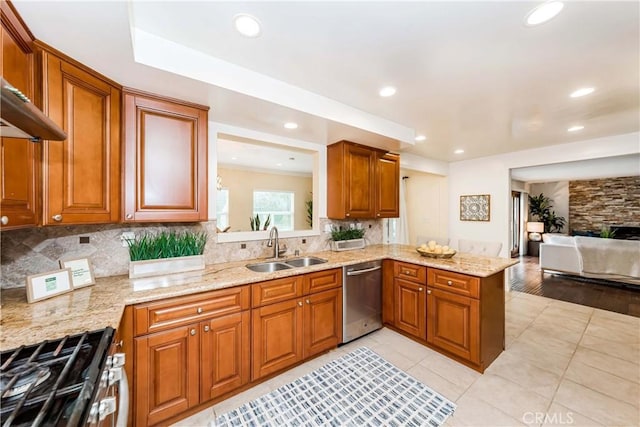 kitchen featuring brown cabinets, appliances with stainless steel finishes, open floor plan, a sink, and a peninsula