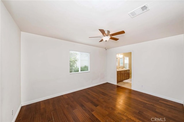 empty room featuring wood finished floors, visible vents, and baseboards