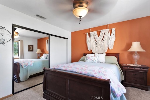 bedroom with a ceiling fan, light colored carpet, a closet, and visible vents