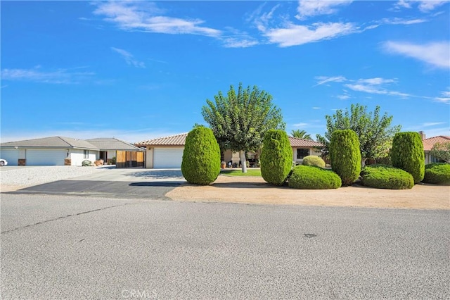 view of front of property featuring a garage, concrete driveway, a tile roof, and a residential view