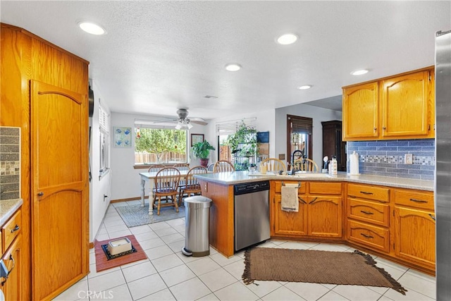 kitchen featuring a peninsula, tasteful backsplash, stainless steel appliances, and light countertops