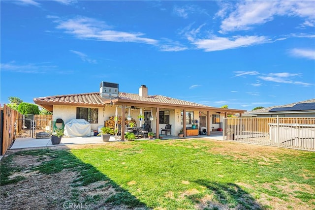 rear view of house featuring a fenced backyard, a tiled roof, a lawn, and a patio