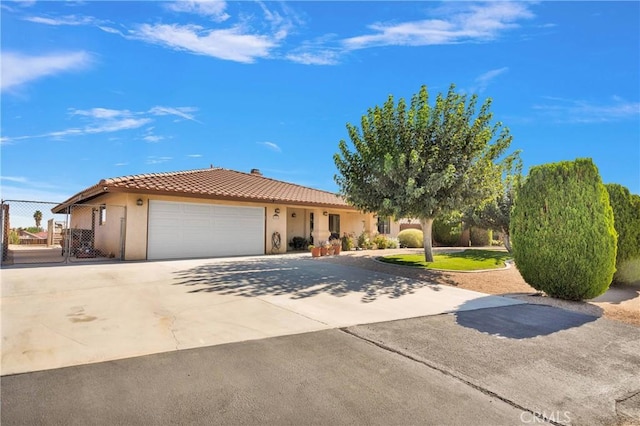 view of front of property featuring stucco siding, fence, a garage, driveway, and a tiled roof