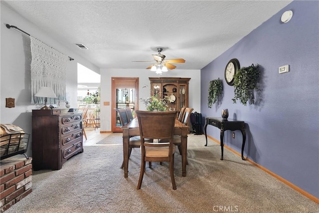 dining space featuring baseboards, visible vents, a textured ceiling, and light colored carpet