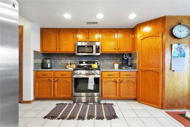 kitchen with tasteful backsplash, visible vents, brown cabinets, stainless steel appliances, and light countertops