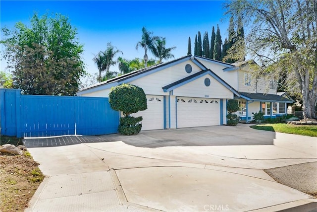 view of front of house with driveway, an attached garage, and fence