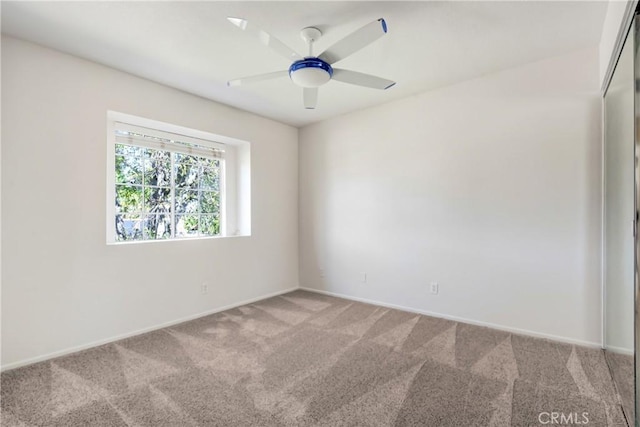 spare room featuring ceiling fan, carpet floors, and baseboards