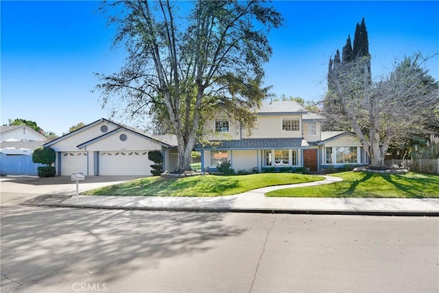 traditional-style house featuring an attached garage, driveway, fence, and a front lawn