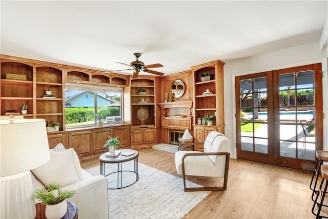 living area with ceiling fan, french doors, and light wood-style floors