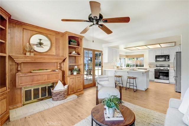 living room with light wood-style floors, french doors, and ceiling fan