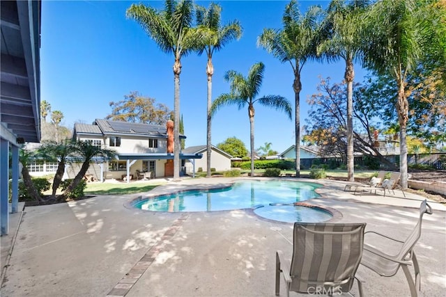 view of swimming pool featuring a pool with connected hot tub, a patio, and fence