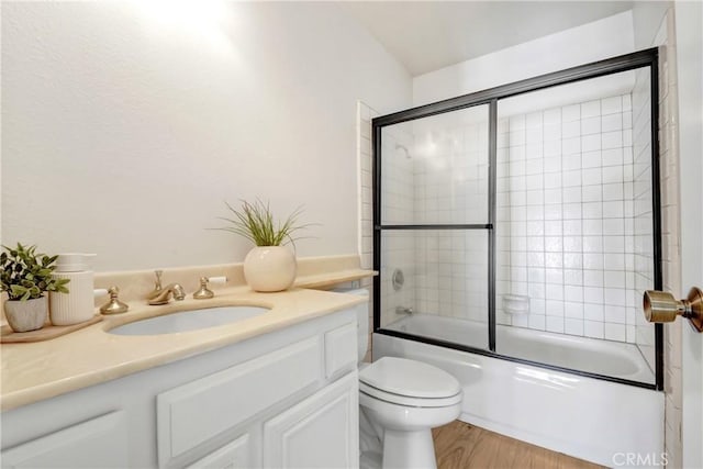 bathroom with toilet, shower / bath combination with glass door, wood finished floors, and vanity