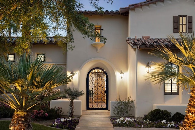 view of exterior entry with a tile roof and stucco siding