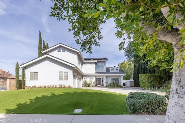 view of front of home featuring solar panels, a front yard, driveway, and stucco siding